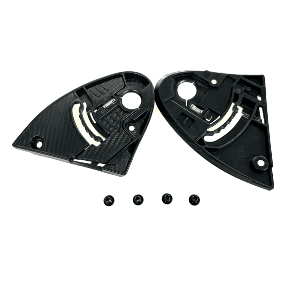 Black plastic gear mechanisms, disassembled into two main components, placed side by side. Four small black screws are aligned in a row below the components. The parts have various cutouts and gear-like structures, suggesting they are elements of a larger machine or device.