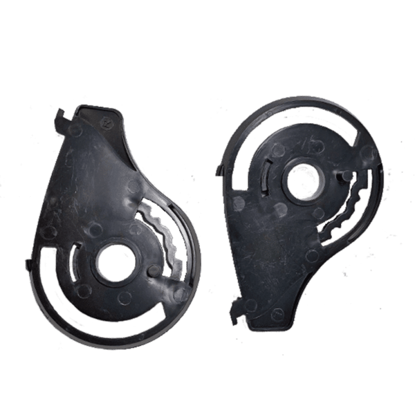 Two black plastic mechanical parts with circular and curved features are shown. The parts appear to be halves of the CX950 and CX950 V2 Shield Pivot Kit, potentially housing components like gears or a belt mechanism. The background is plain and neutral.